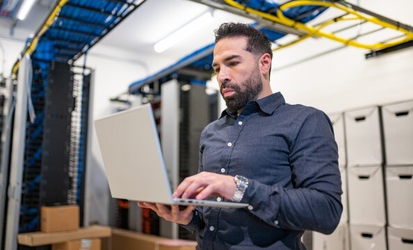 En mand, der holder en HP-laptop og skriver på den, mens han står op.